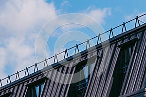 Modern house with a metal roof and windows against blue sky.