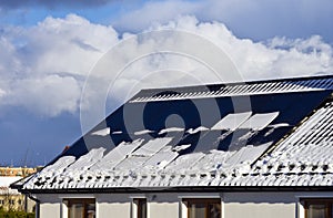 Modern house roof with solar panels covered with snow