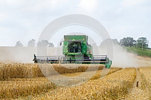 Modern 9780i cts john deere combine harvester cutting crops corn wheat barley working golden field