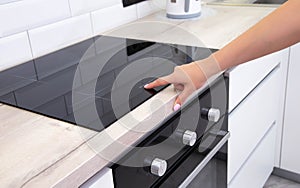 Modern induction hob in the kitchen. A woman& x27;s hand sets the heating power of the burner, ceramic