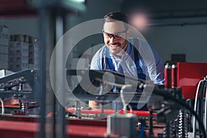 Modern industrial machine operator working in factory. Worker on the machine