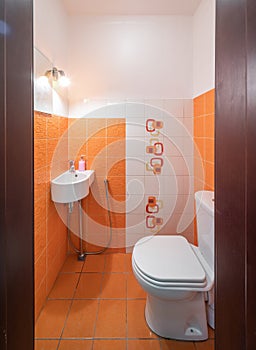 Modern interior of bathroom. Orange tile. Sink and toilet.