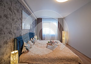 Modern interior of bedroom in luxury apartment. Breakfast on bed.