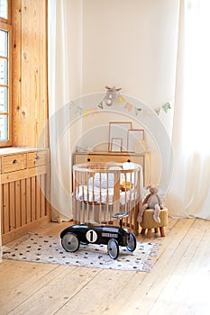 Modern interior of a children`s bedroom. Copy space. Hygge. Kindergarten. Cozy Scandinavian lights baby room: wooden crib with bed