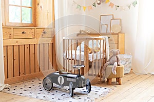 Modern interior of a children`s bedroom. Copy space. Hygge. Kindergarten. Cozy Scandinavian lights baby room: wooden crib with bed