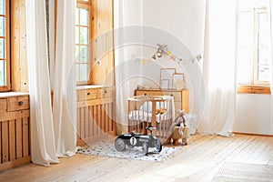 Modern interior of a children`s bedroom. Copy space. Hygge. Kindergarten. Cozy Scandinavian lights baby room: wooden crib with bed