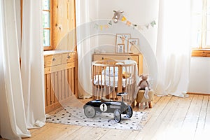 Modern interior of a children`s bedroom. Copy space. Hygge. Kindergarten. Cozy Scandinavian lights baby room: wooden crib with bed