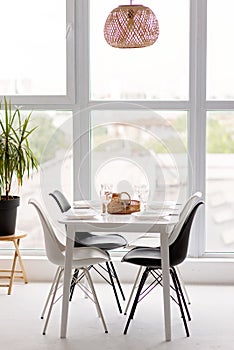 Modern interior of a cozy dining room kitchen, white furniture, against the background of a panoramic window. Conceptual decor