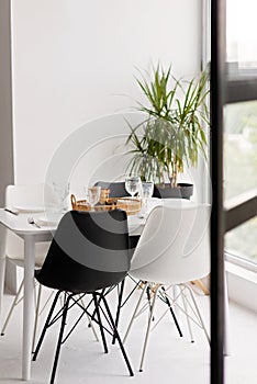 Modern interior of cozy kitchen, dining room, white furniture, chairs, bowls. Conceptual decor design, advertising, home loan