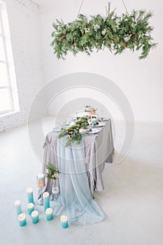 Modern interior design. Beautiful vintage dining table with decorations, flowers, candles and laying near the window