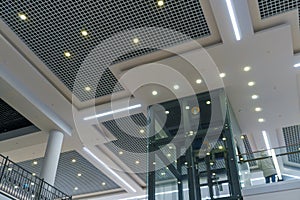 Modern interior design inside the mall. Glass transparent elevator in the business center. View of the ceiling, moldings and LED