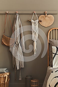 Modern interior design of stylish bedroom with decoration, neutral macrame, clothes hanger, dressing-gown, basket, beautiful bed.