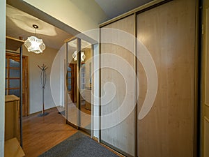 Modern interior of hall in apartment. Wardrobe with sliding door. Wooden door.