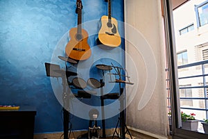 Modern interior of a music studio at home. Acoustic and electric guitars hanging on blue color wall and drum set