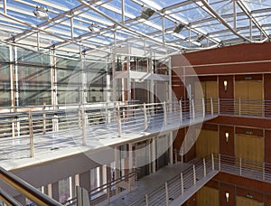 Modern interior of office building with glass walls and roof, corridor and lifts, natural sun light