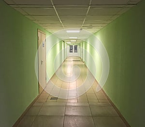 Modern interior in office building. Long empty hall with distant doors and office entrance.