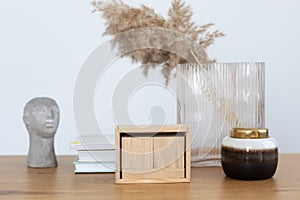 Modern interior workspace with books, vase with dried flowers, blank blocks wooden calendar and statuette in form of head figure.