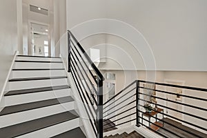 Modern iron staircase in a spacious foyer designed with grey hardwood floor