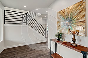 Modern iron staircase in a spacious foyer designed with grey hardwood floor