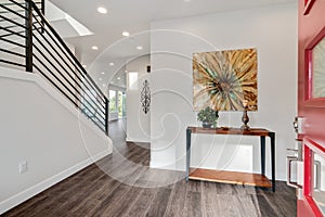 Modern iron staircase in a spacious foyer designed with grey hardwood floor