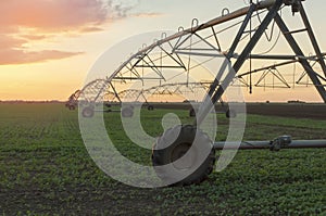 Modern irrigation system on a farm field at sunset.
