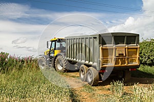 Modern JCB fast trac tractor pulling green yellow trailer