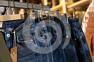 Modern jeans hanging on clothing rack in shop