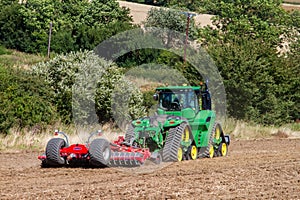 Modern john deere caterpilla tractor cultivating English crop field