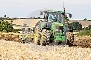 Modern John Deere tractor pulling a plough