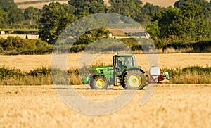 Modern john deere tractor Tractor spraying field stubble crops