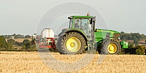 Modern john deere tractor Tractor spraying field stubble crops