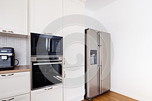 Modern kitchen area, wooden floor with modern refrigerator and appliances