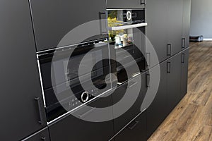 Modern kitchen with black fronts, built in oven and microwave, vinyl panels on the floor.