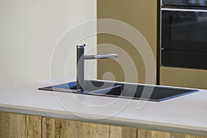 Modern kitchen, the black water tap and kitchen sink. Kitchen island with a tap and gray worktop