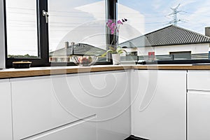 A modern kitchen with built in cabinets against the wall with white fronts, vinyl panels on the floor.