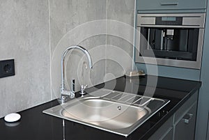 Modern kitchen  with chrome faucet, water tap, black kitchen table, coffee mashine and  kitchen sink