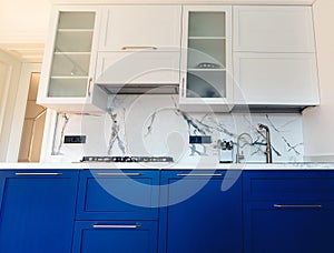 Modern kitchen clean interior design. Luxury blue and white furniture of kitchen with marble tiled backsplash