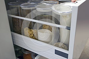 Modern kitchen countertop with food ingredients. Top view of drawers with spices organized inside. Jars with food in the