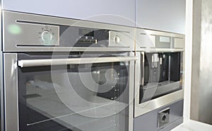 Modern kitchen with electric oven, electic stove and coffee machine in light blur.