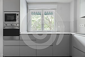 Modern kitchen with gray wooden cabinets and white stone worktops