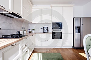 Modern kitchen interior with hardwood floors and wooden white creamy furniture