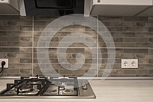 Modern kitchen interior with stainless steel gas cook-top and grey tile brick backsplash