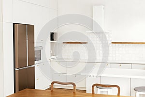 Modern kitchen interior. Stylish white kitchen cabinets with brass knobs, granite island and appliances in new scandinavian house
