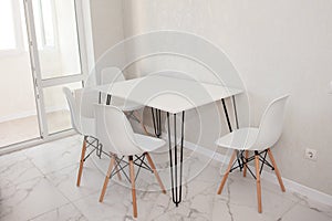 Modern kitchen interior with white dining table with four white chairs. Modern design, dining table and chairs in kitchen near