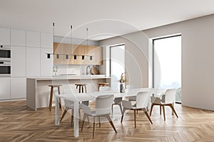 Modern kitchen interior with white walls  a wooden parquet floor and white countertops. A long table with chairs near it. 3d