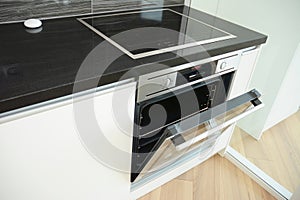 Modern kitchen with open door electric oven and induction cooktop, electic stove