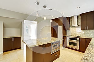 Modern kitchen room with matte brown cabinets and granite trim.