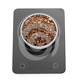Modern kitchen scale with bowl of tasty granola isolated on white