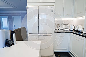 Modern kitchen with white cabinetry, refrigerator, oven, and table