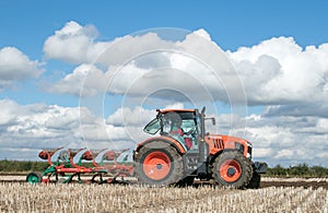 Modern Kubota tractor pulling a plough
